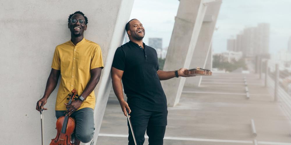 Members of Black Violin posing near the wall