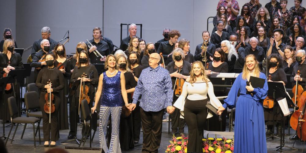 performers standing in front of orchestra