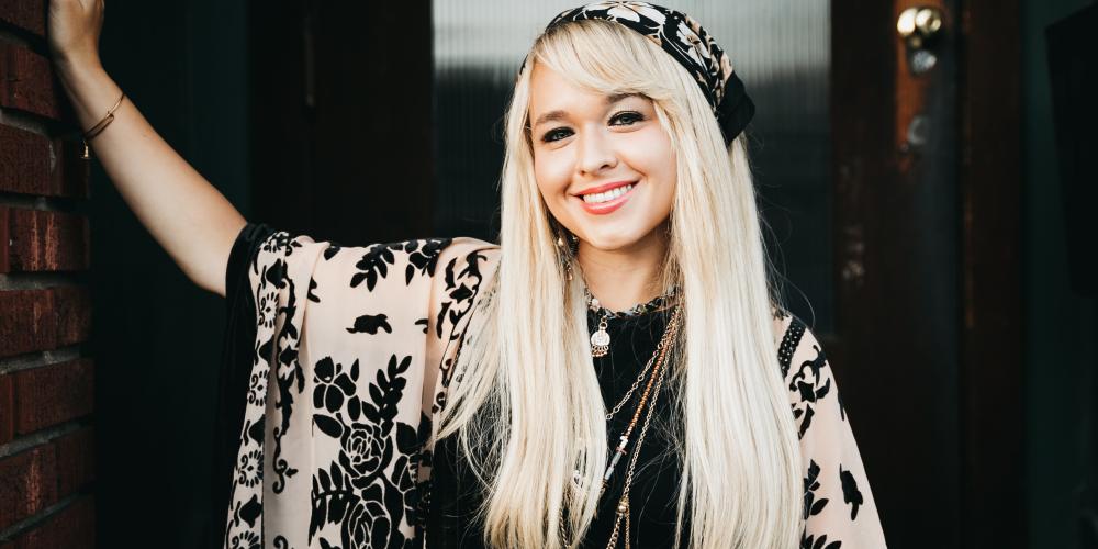 Christie standing in a doorway with patterned head scarf and matching blouse