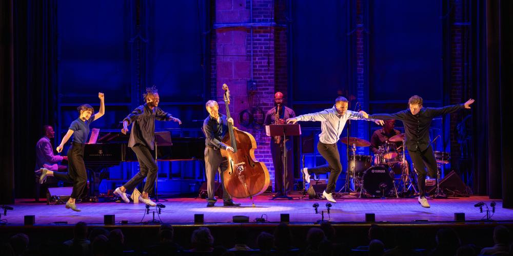 five dancers on a purple backlit stage