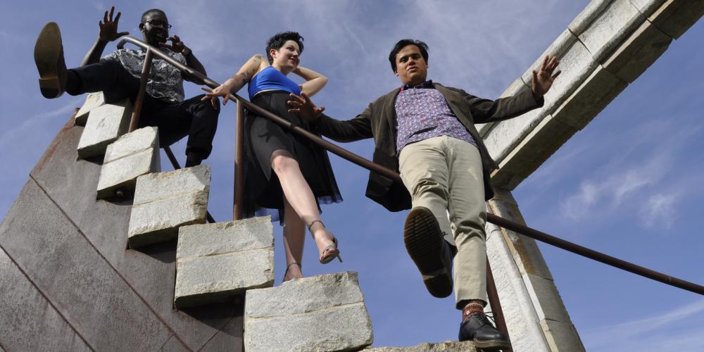 Three people - a woman and two men playfully walk down a set of MC Escher like stairs