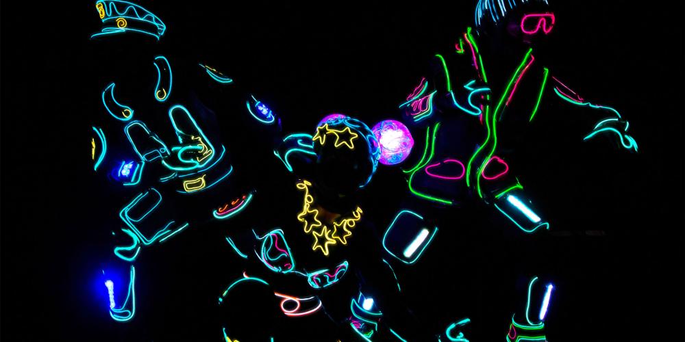 Three iLuminate performers lit as a cop, female super hero and bystander