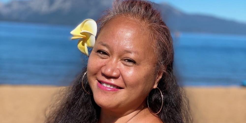 Kami Valdez on a beach wearing Hawaiian sarong with a flower in her hair.