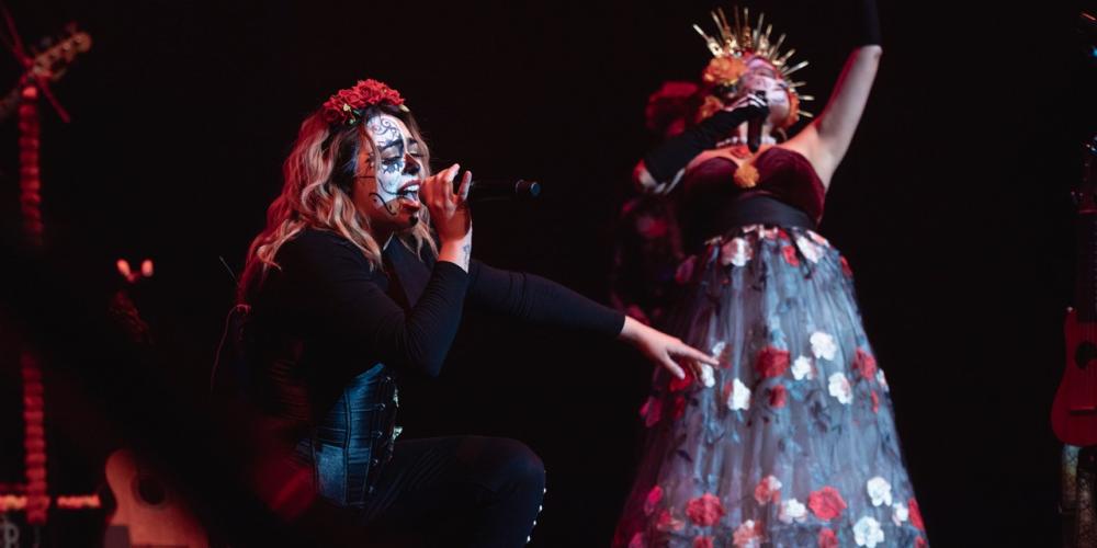woman singing with skeleton makeup on and a woman to the right dancing