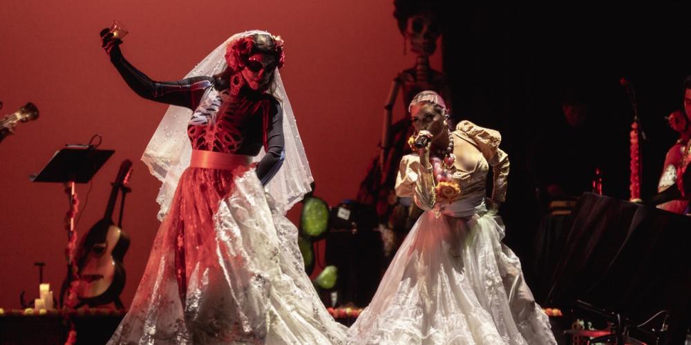 two women dancing with skeleton makeup and white dresses on stage