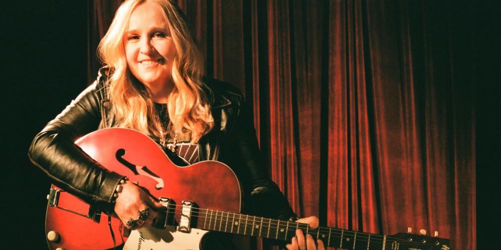 Melissa Etheridge sitting and holding a guitar