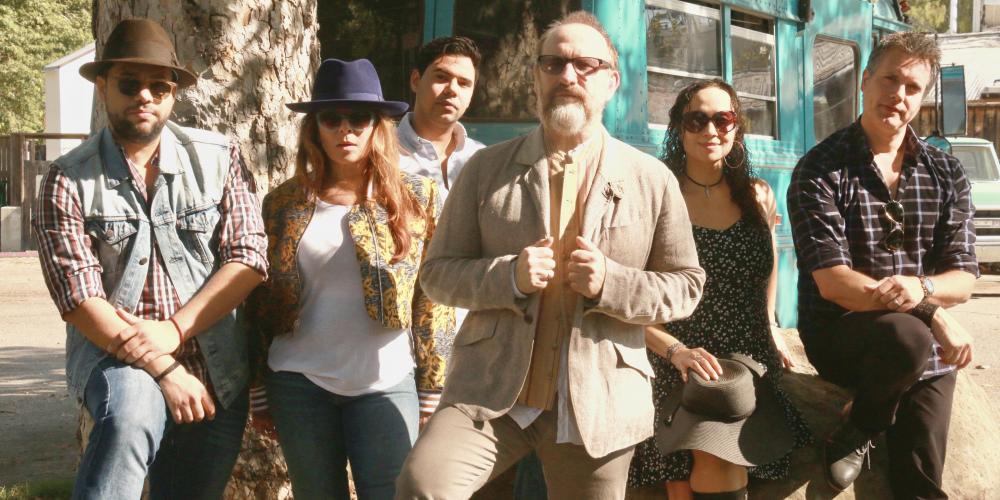 Men at Work Group Photo - Members standing outside in front of a teal colored bus