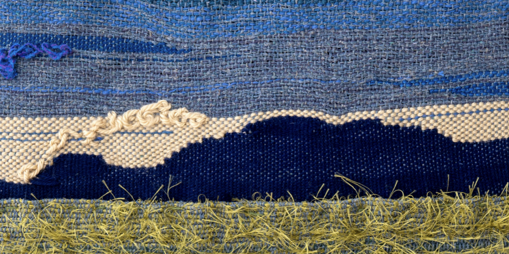 fabrics of blue white and green/yellow making up an image of a mountain or hill in almost darkness