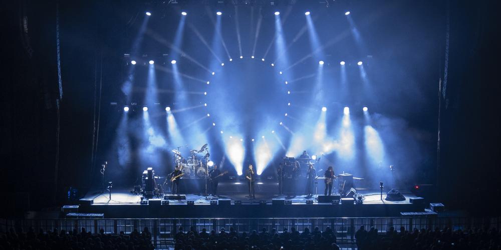 Wide shot of performers on a stage with dramatic blue lights
