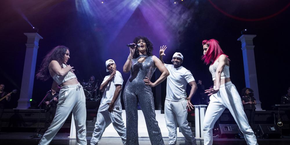 Belinda Davids performing on stage surrounded by dancers