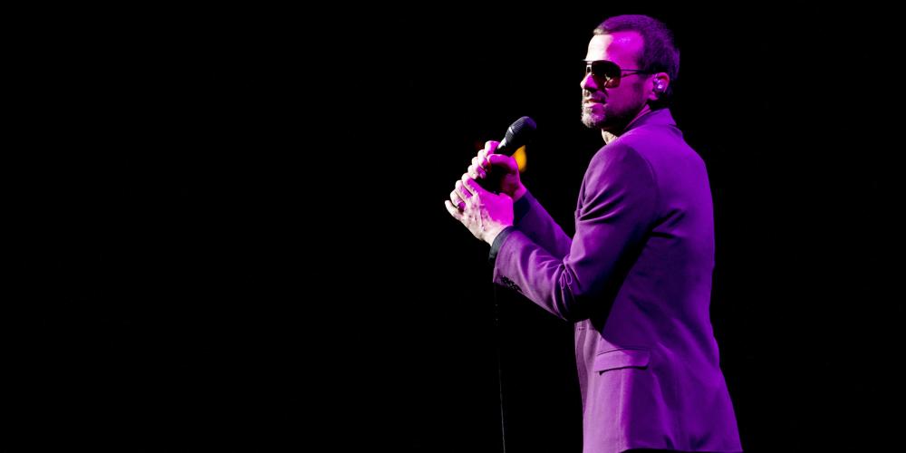 Performing on stage with purple jacket and sunglasses