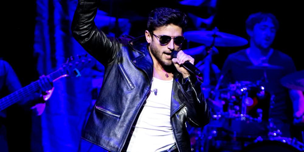 Performing on stage with black leather jacket, jeans and sunglasses