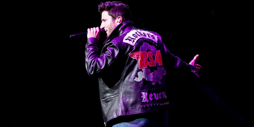 Performing on stage with black leather jacket with red rose on back