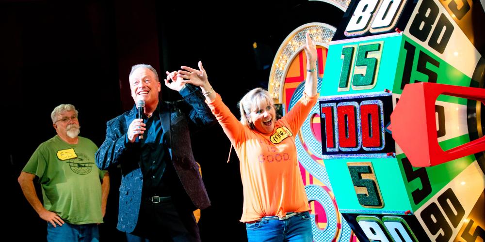 excited woman with her arms up looking at The Price is Right wheel 
