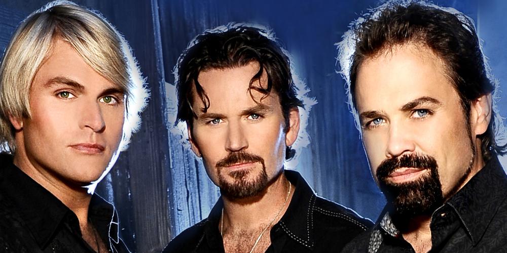 Three men - two with brown hair and beards, one with blond hair, wear black shirts