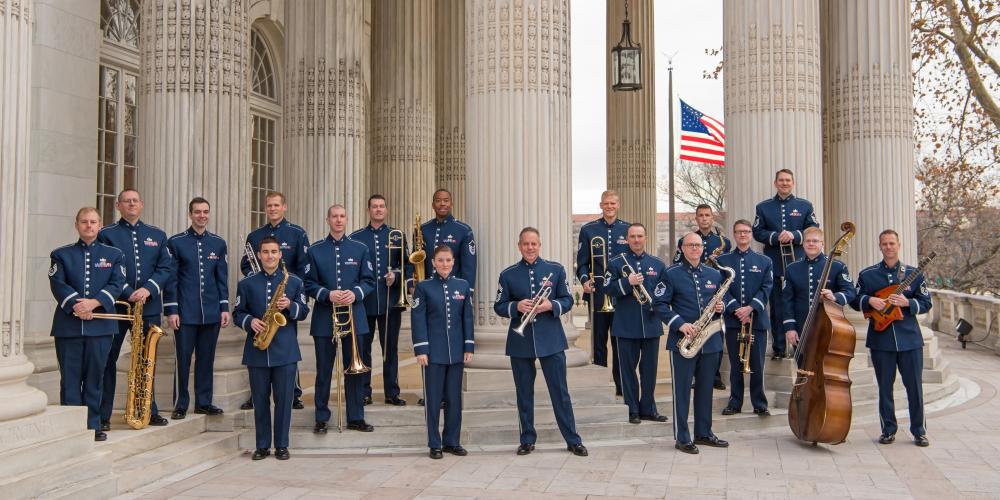 18 men in dress blues pose with their instruments