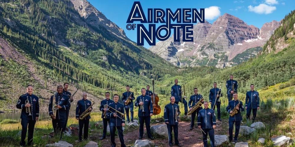 United States Air Force Band Airmen of Note standing at the base of a mountain, in uniform holding their instruments