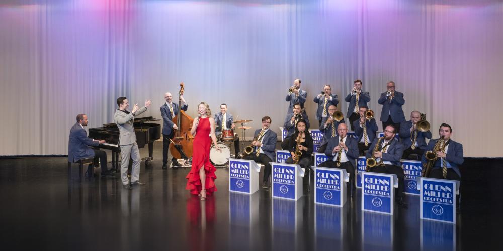 Man and woman singing in front of orchestra on stage