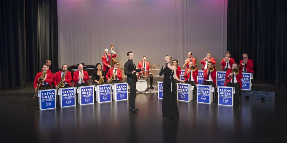 Man and woman singing in front of seated orchestra