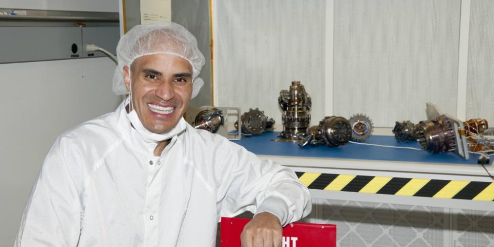 Kobie Boykins dressed in white smiling in front of rover wheels