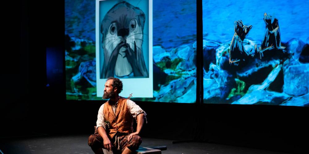 Man sitting on stage with a photo of otter on a projected screen