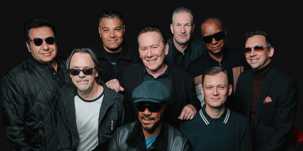 Group of 9 men dressed in black and gray attire with a black background