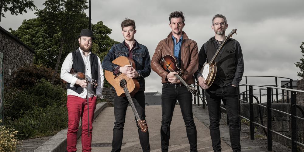 We Banjo 3 standing on a village road with their instruments