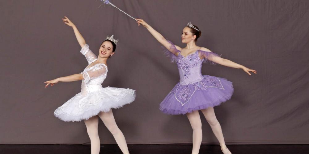 Two female ballet dancers-one dressed in white, the other in purple