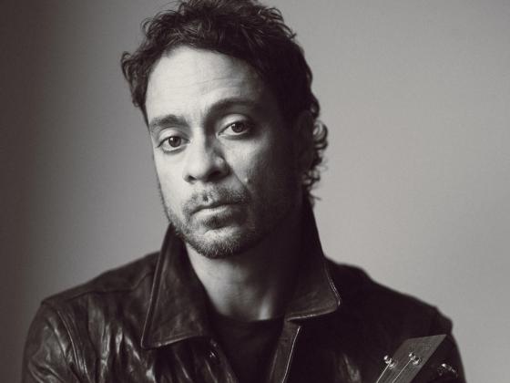 man with curly hair wearing all black clothing