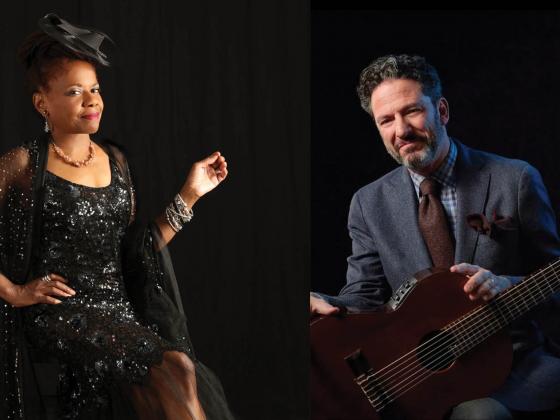 Chandler Center for the Arts presents John Pizzarelli and Catherine Russell in Billie and Blue Eyes A woman in a black dress sits on a chair, posing with a smile, and a man in a gray suit sits with his guitar