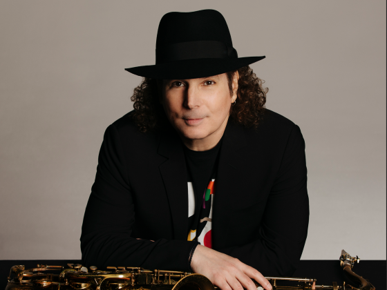 Boney James in a black hat and jacket with his saxophone in front of him