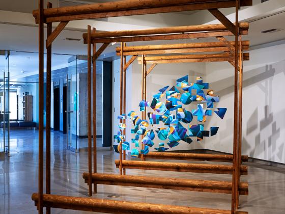 large, square, wooden structure with blue material hanging in small amounts in the center of the squares.