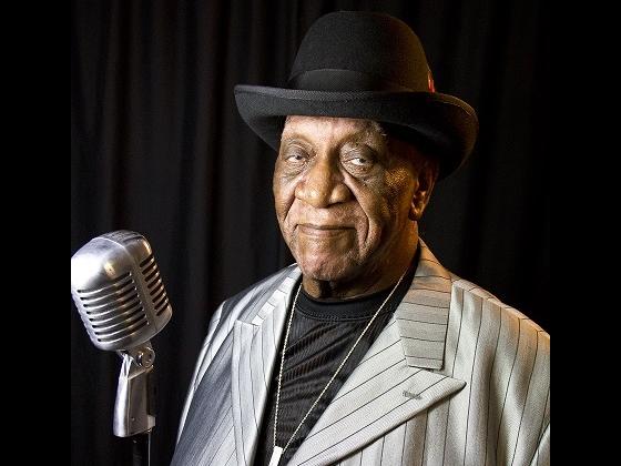 Big Pete Pearson wearing a silver suit and black bowler hat standing behind an old style microphone Big Pete Pearson wearing a silver suit and black bowler hat standing behind an old style microphone