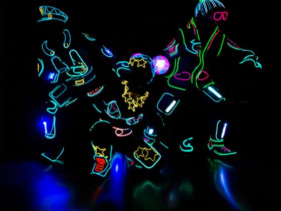 Three iLuminate performers lit as a cop, female super hero and bystander