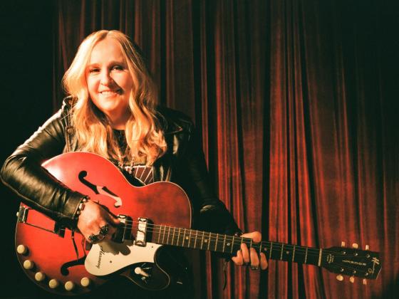 Melissa Etheridge sitting and holding a guitar