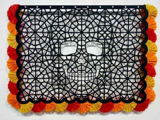 Michelle Emami: Both, Neither and All of the Above black rectangle with decorative cut outs making up a skeleton head. The black rectangle has red, yellow and orange fluffy decoration around the outside.