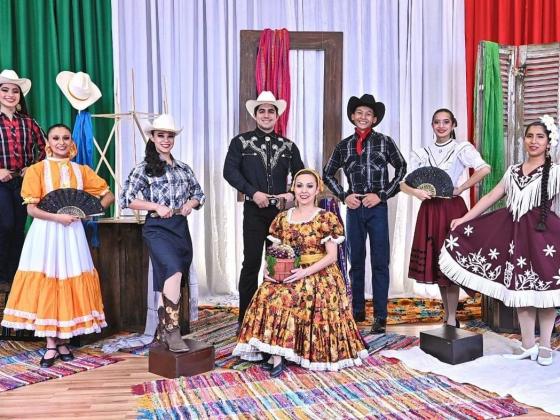 Seven women and three men pose in colorful costumes traditional for the northern region of Mexico, including cowboy hats and ribbon-trimmed skirts
