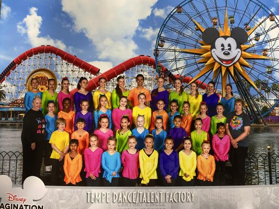 Tempe Dance students dressed in different primary color t-shirts posed in front of Disney roller coaster