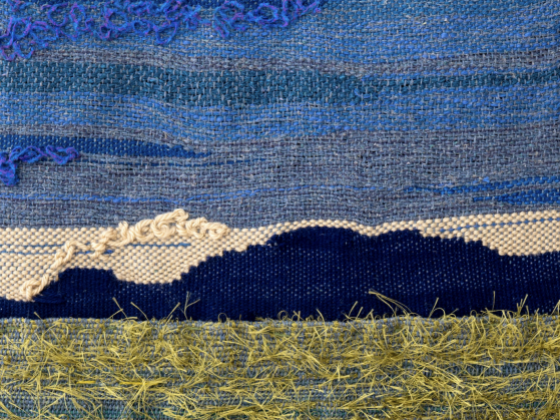 fabrics of blue white and green/yellow making up an image of a mountain or hill in almost darkness