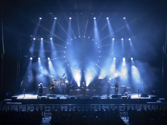 Wide shot of performers on a stage with dramatic blue lights