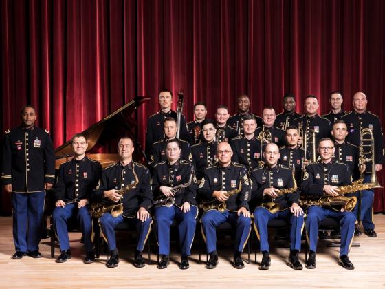 group of men in uniforms surrounding a piano and in front of a red curtain