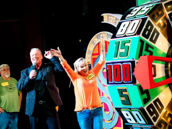excited woman with her arms up looking at The Price is Right wheel 