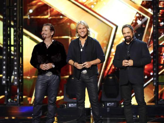 The Texas Tenors on stage with a golden light background