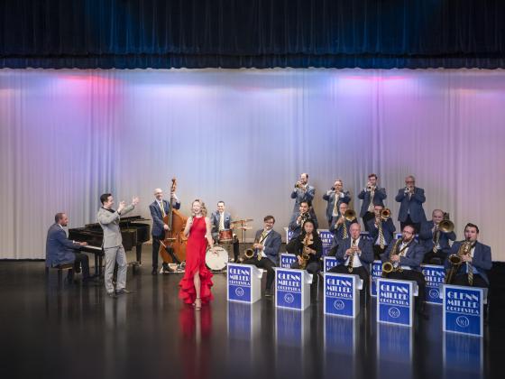 Man and woman singing in front of orchestra on stage
