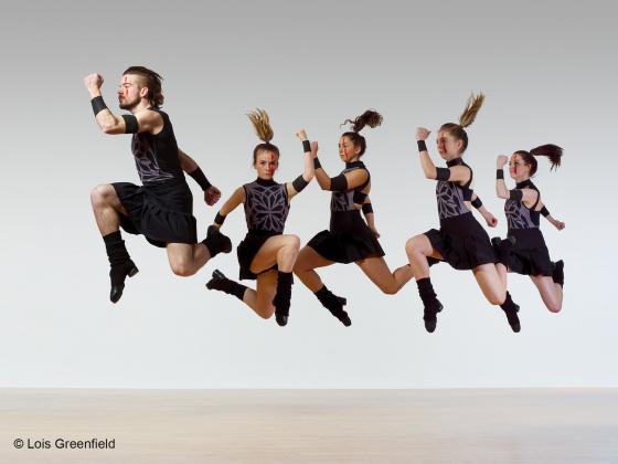 Five Members, one male and four females, of Trinity Irish Dance Company leaping forward through the air