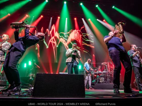 singer and two saxophonists on stage with green and red stage lights