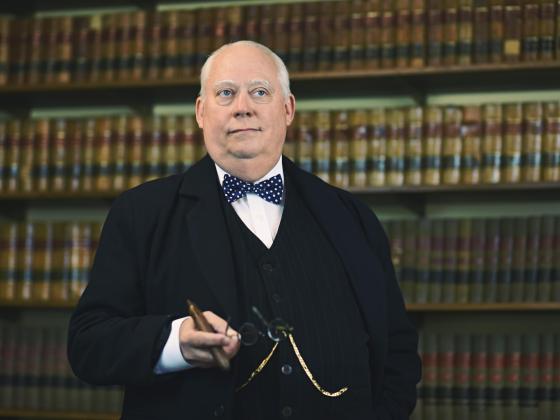 Winston Churchill: Standing in a library holding a cigar Winston Churchill: Man of the Century at Chandler Center for the Arts