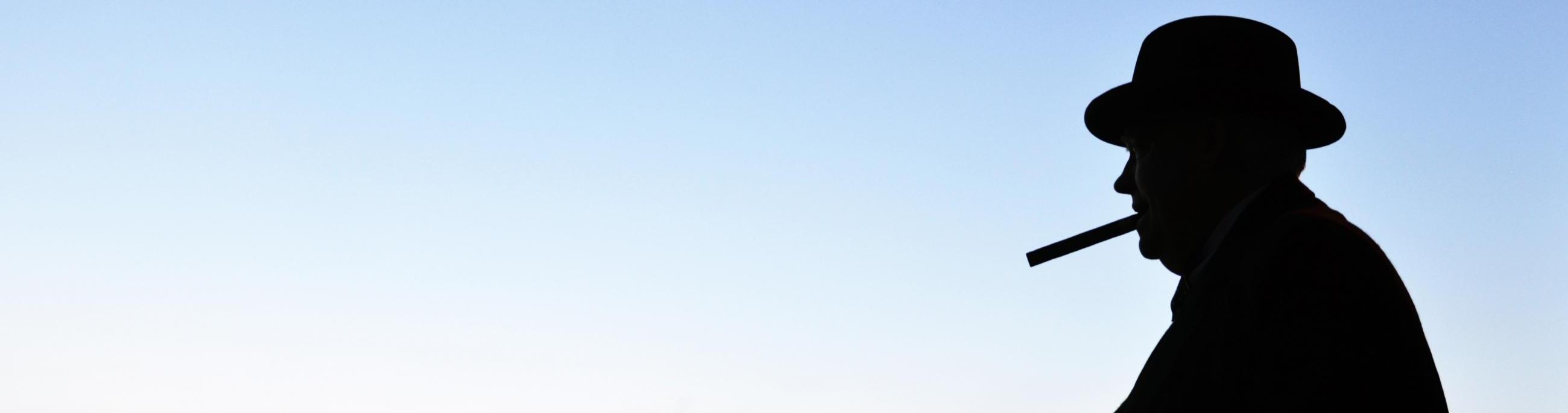 A man stands in silhouette against a sunset over the water