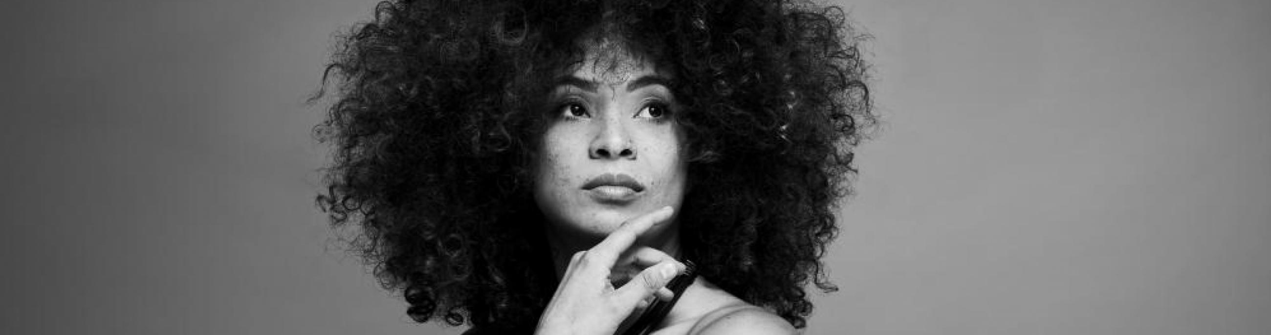 In this black-and-white photo, singer Kandace Springs rests her chin on her hand and looks off into the distance.