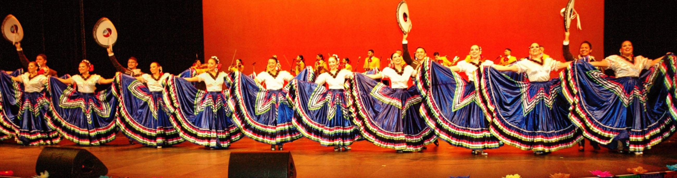 A line of Ballet Folklorico dancers in blue skirts with colorful trim.